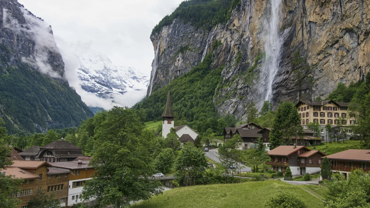 Steep glacial canyon walls rising above a lush alpine river valley