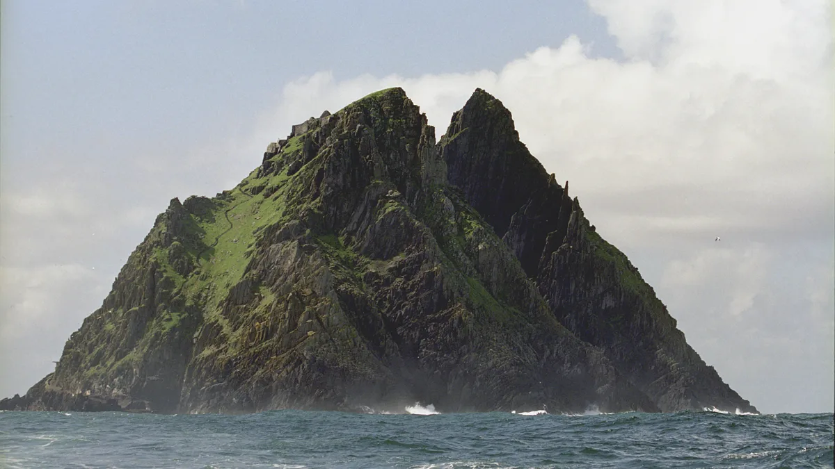 Steep rocky sea stack rising dramatically out of dark ocean swells